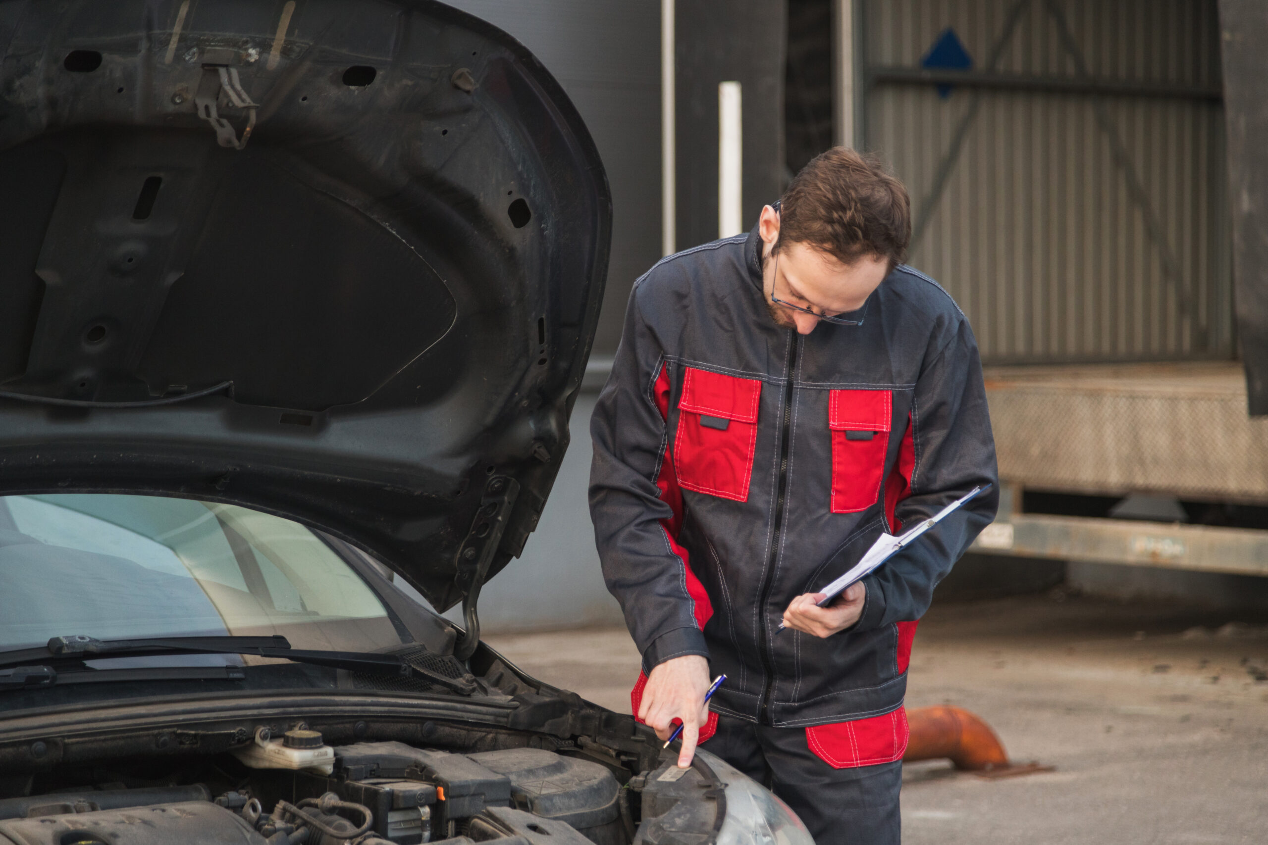 Caucasian Mechanic In Uniform Check Serial Numbers Of Car Elements During Technical Inspection